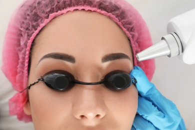 Photo of Woman undergoing laser tattoo removal procedure in salon, closeup