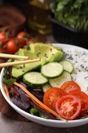 Photo of Delicious poke bowl with vegetables, avocado and mesclun on textured table, closeup