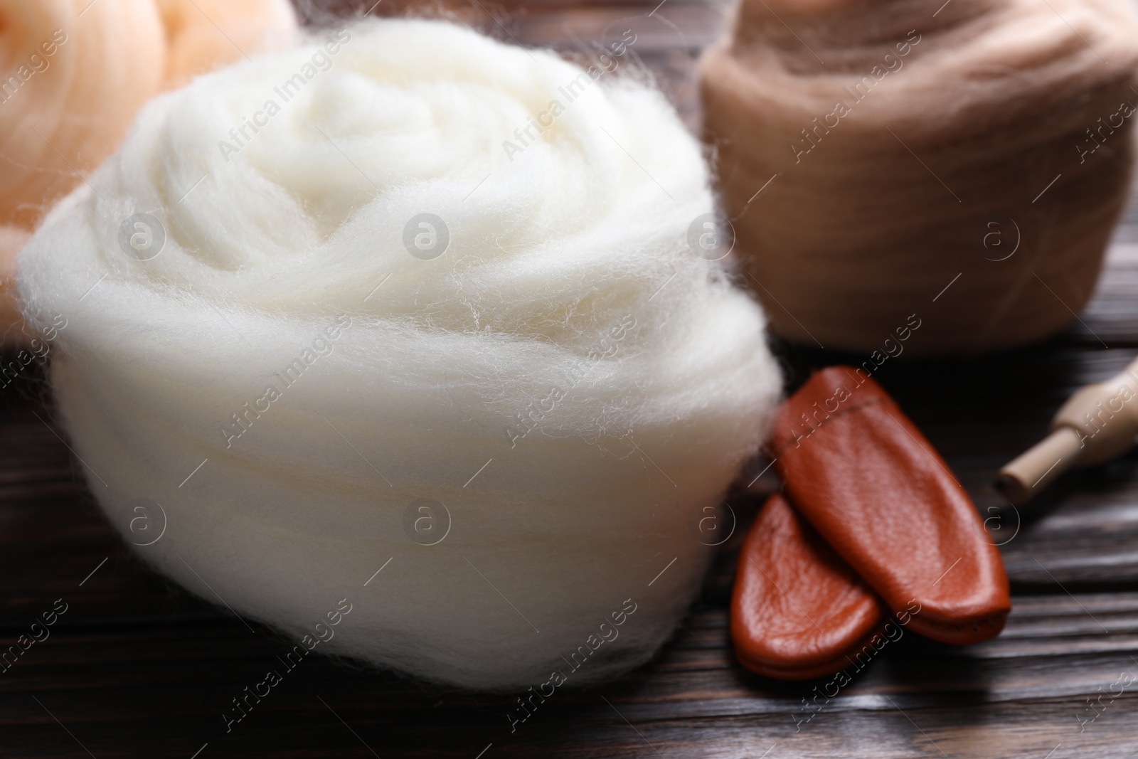 Photo of Colorful felting wool and finger protectors on wooden table, closeup