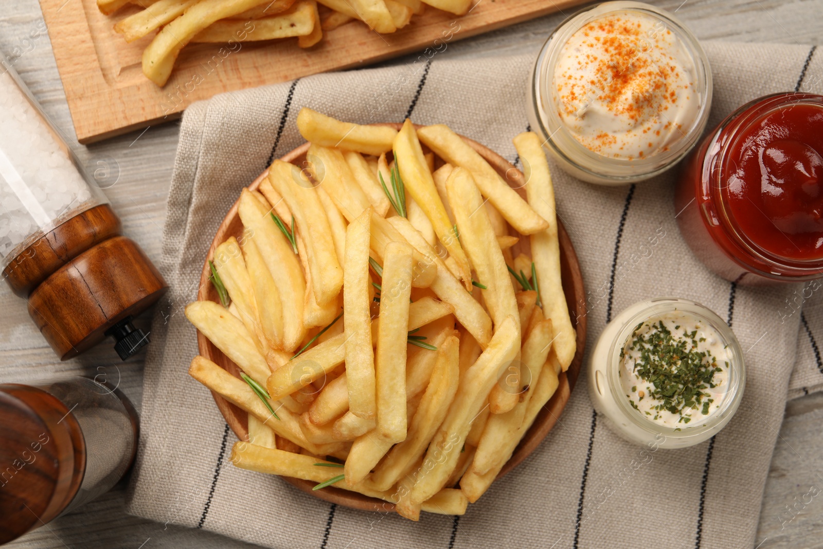 Photo of Delicious french fries served with sauces on light wooden table, flat lay
