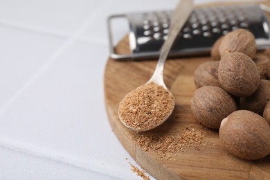 Photo of Spoon with grated nutmeg, seeds and grater on white table, closeup. Space for text