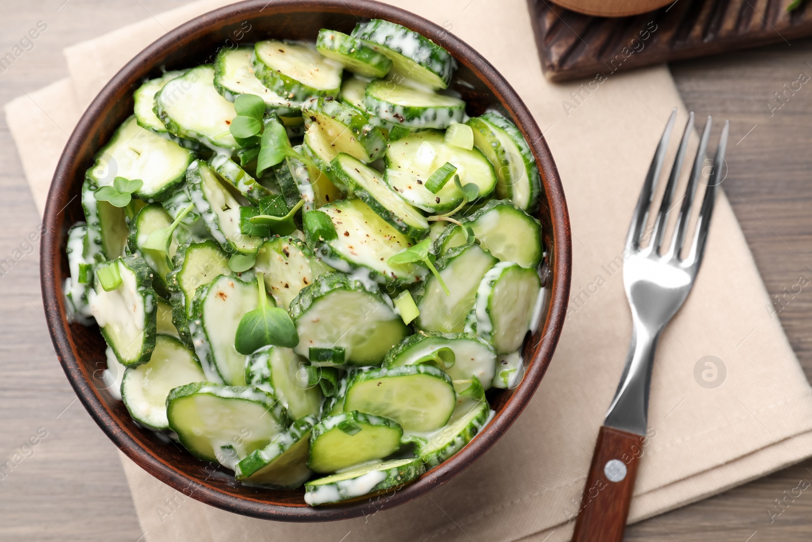 Photo of Delicious cucumber salad served on wooden table, top view