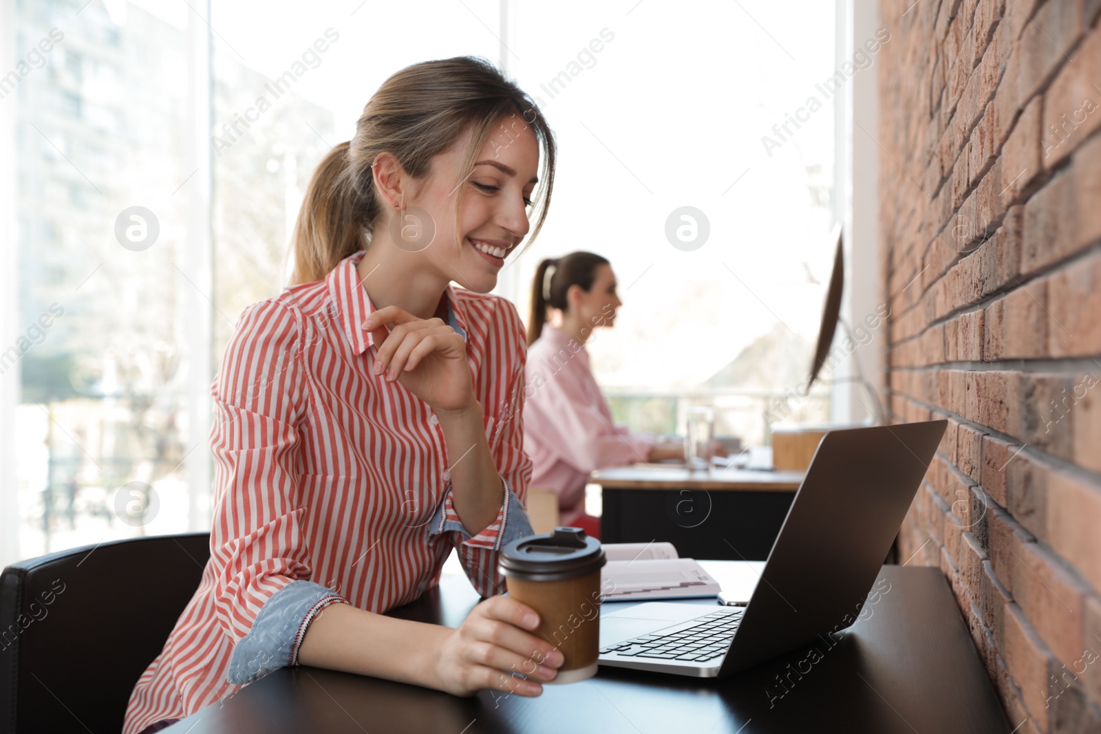 Photo of Young businesswoman using laptop at table in office