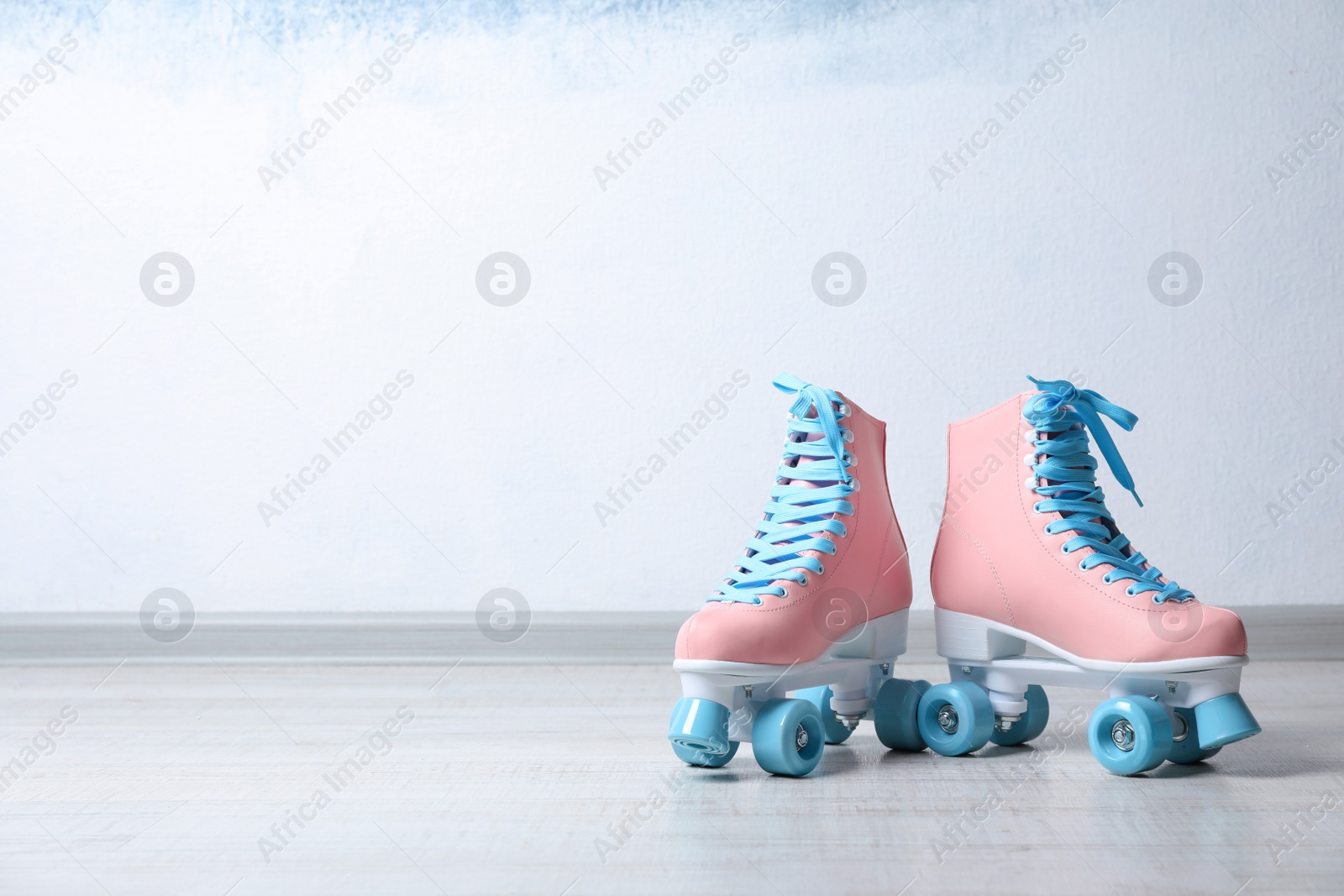 Photo of Vintage roller skates on floor near color wall. Space for text