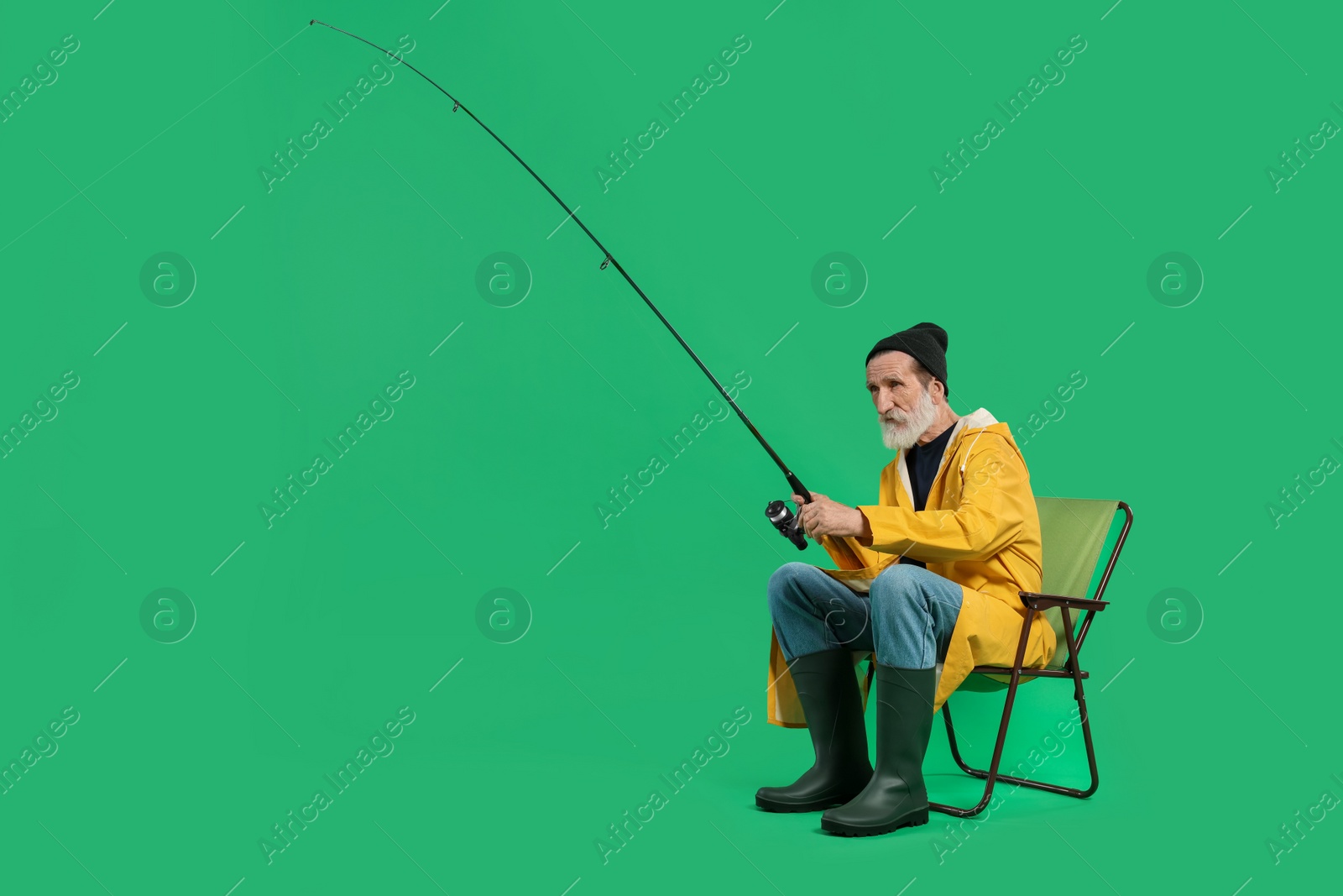 Photo of Fisherman with rod on chair against green background