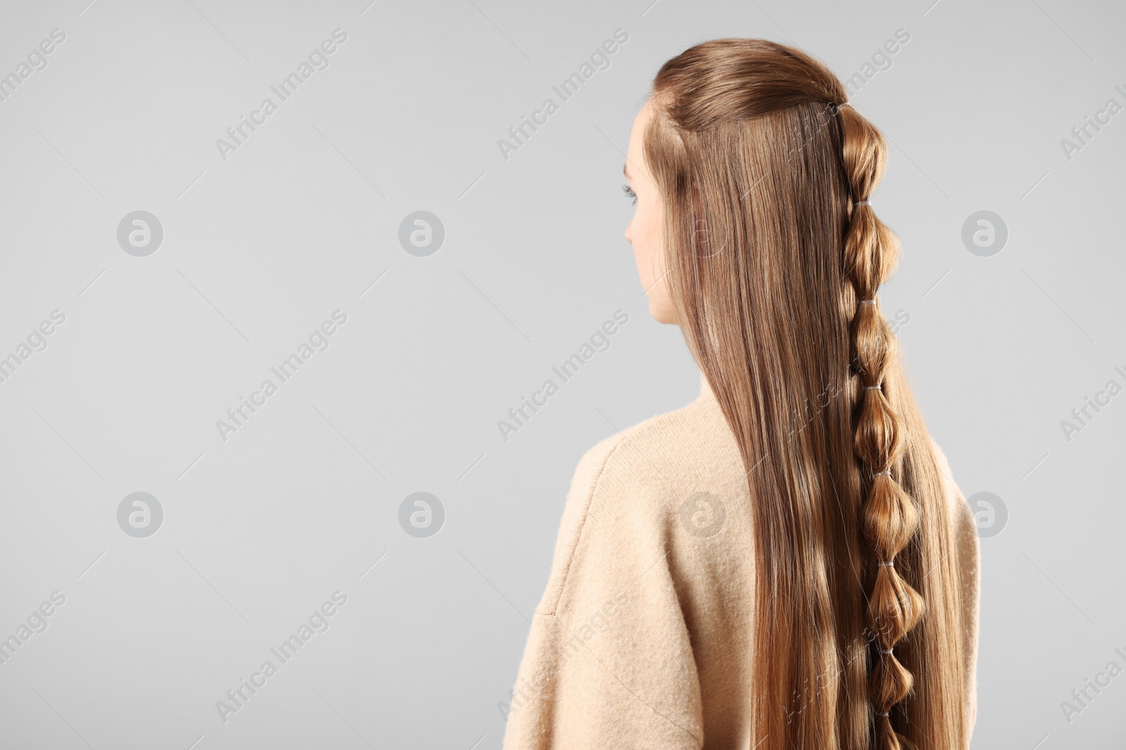 Photo of Woman with braided hair on grey background, space for text