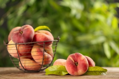 Photo of Fresh ripe donut peaches on wooden table against blurred green background. Space for text
