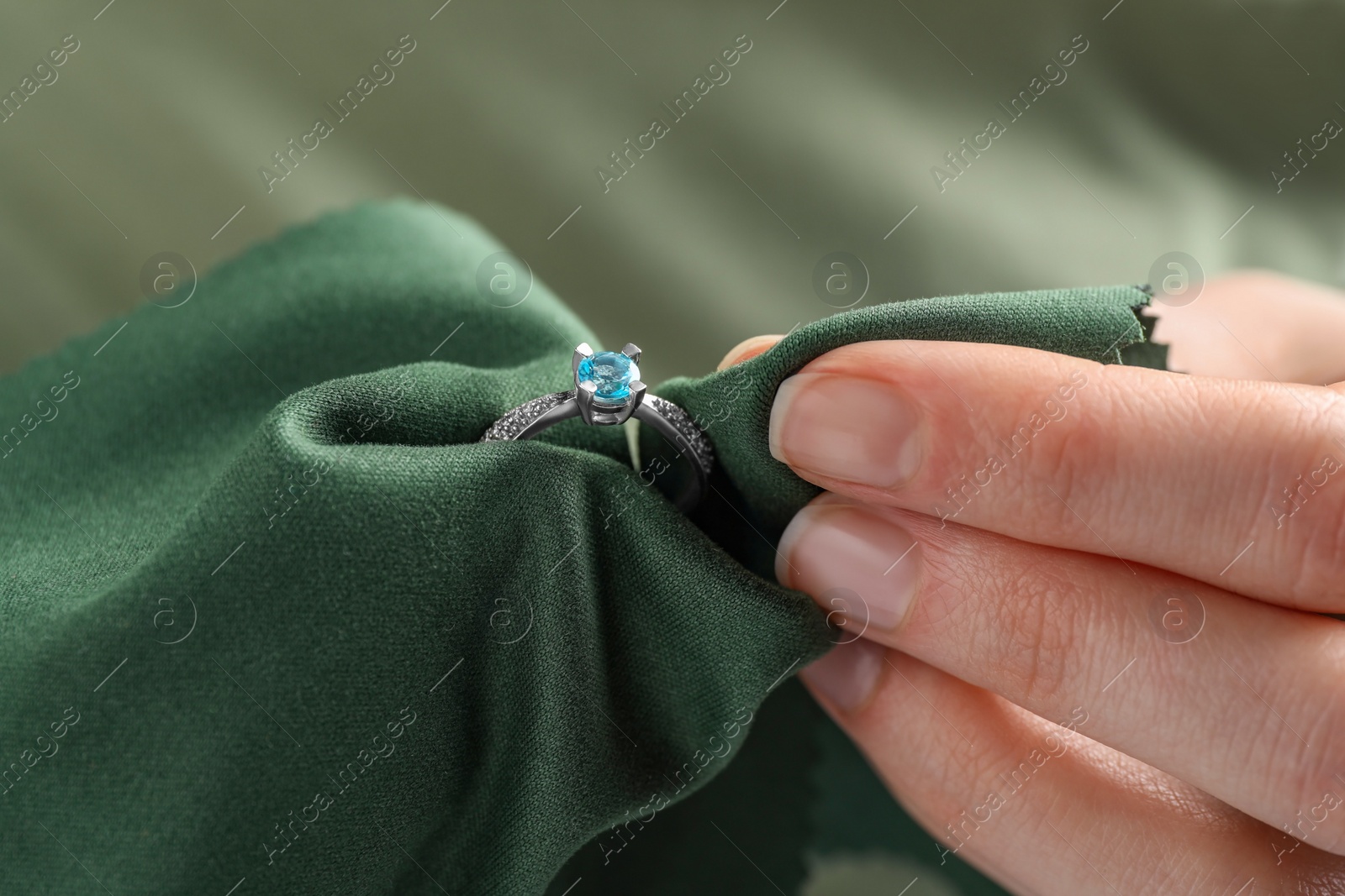 Photo of Jeweler cleaning topaz ring with microfiber cloth, closeup