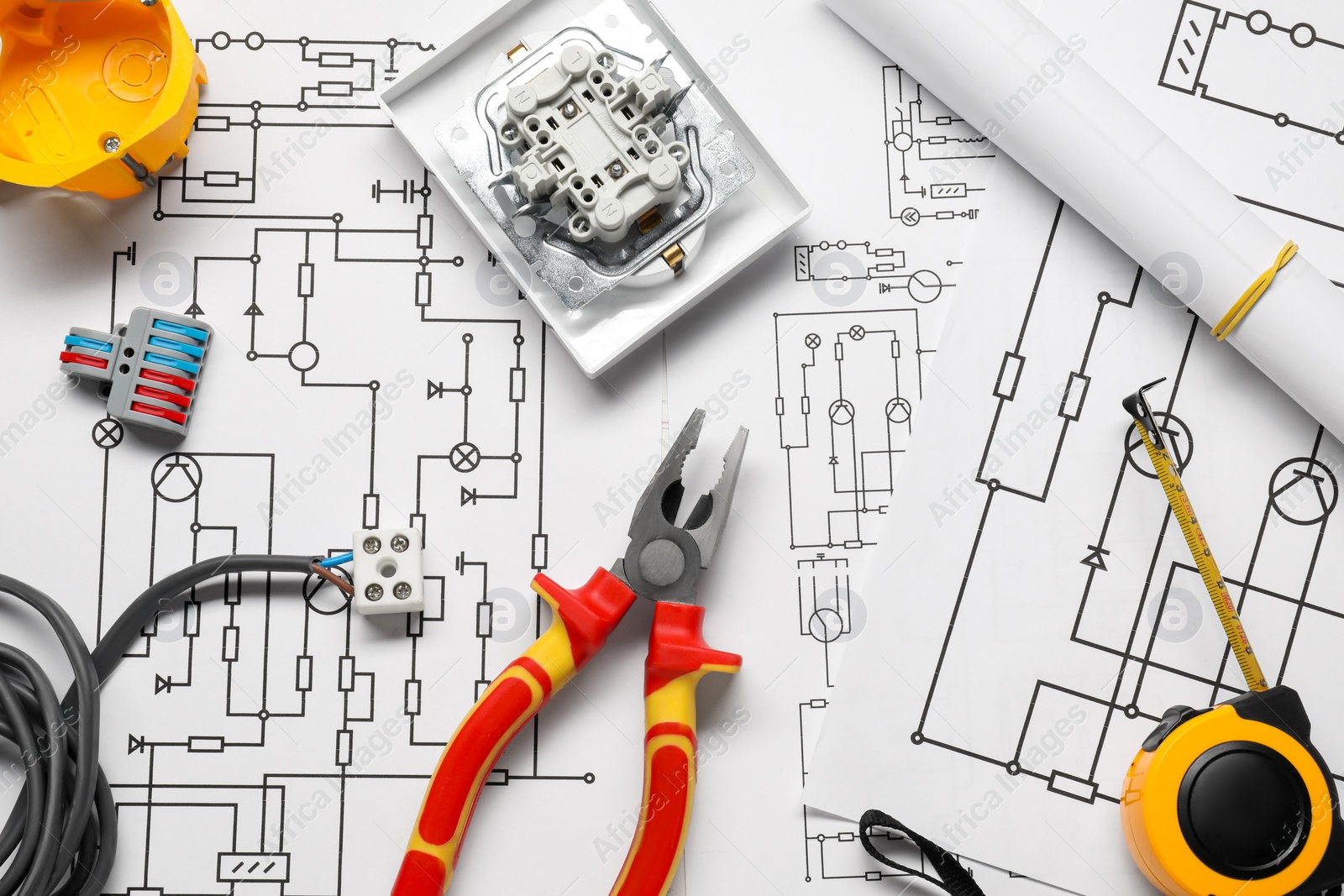 Photo of Different electrician's equipment and pliers on wiring diagrams, flat lay