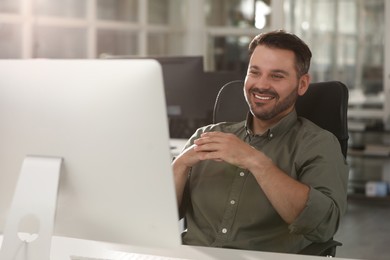 Photo of Happy man using modern computer at white desk in office