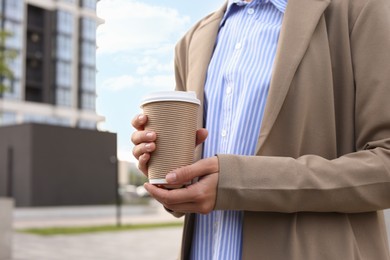 Photo of Coffee to go. Woman with paper cup of drink outdoors, closeup