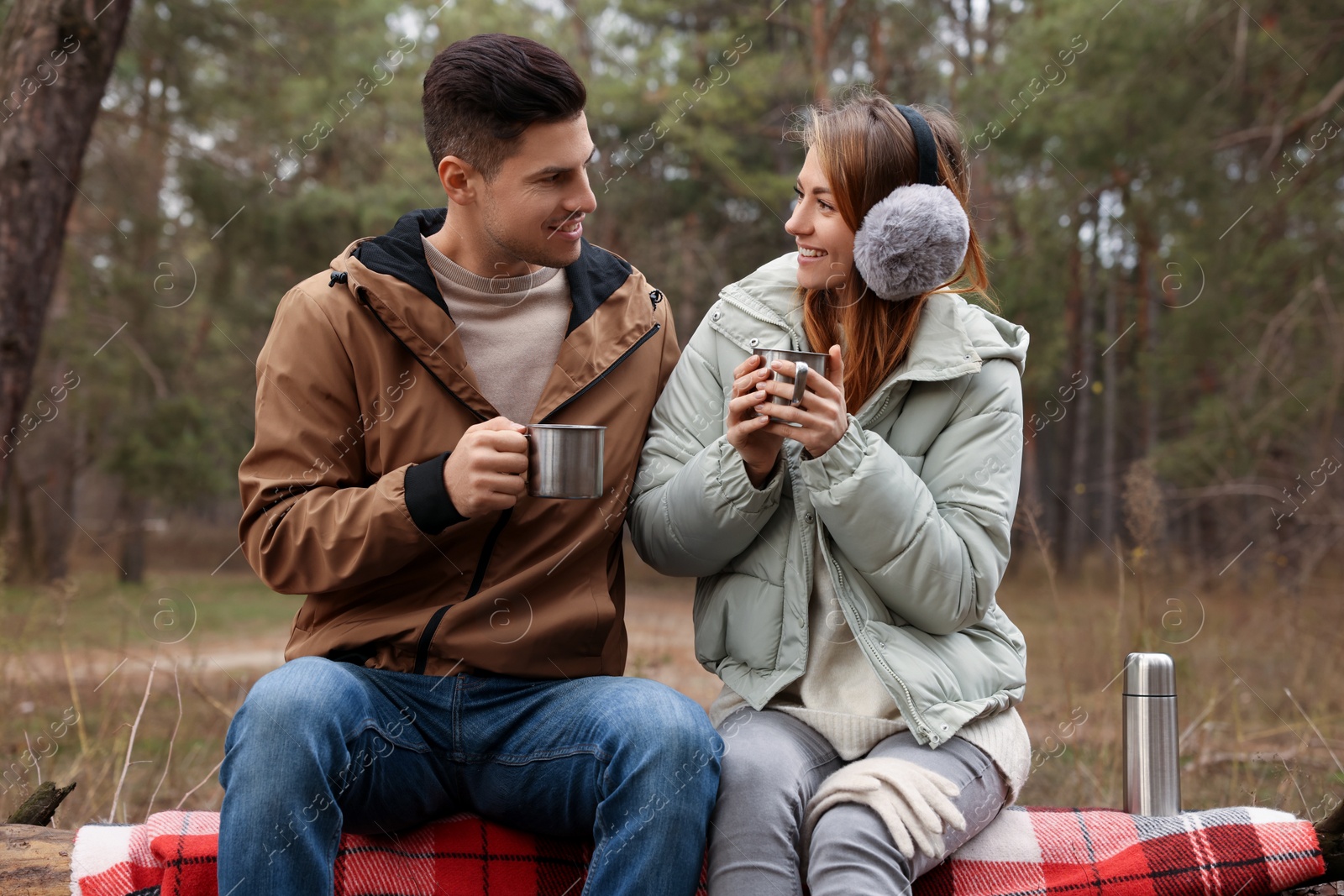 Photo of Happy couple with cups of hot tea spending time together in forest