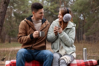 Photo of Happy couple with cups of hot tea spending time together in forest