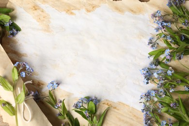 Photo of Beautiful forget-me-not flowers and old parchment, top view