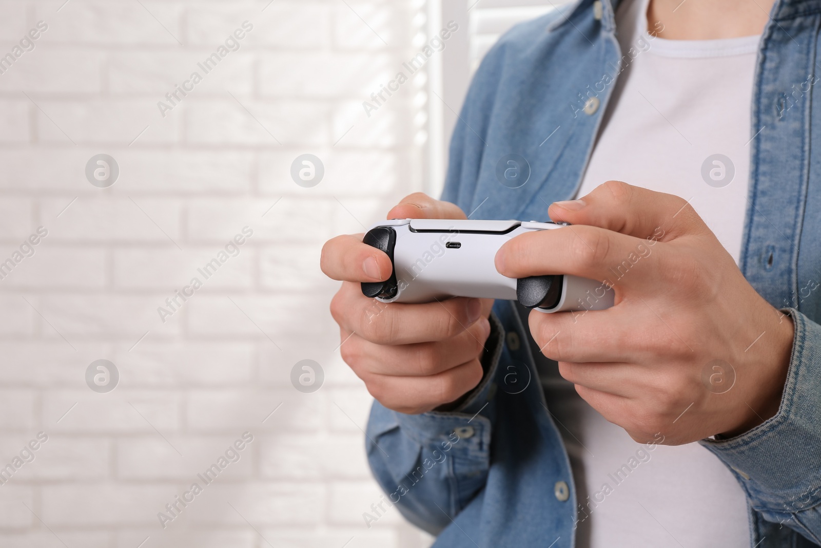 Photo of Man using wireless game controller indoors, closeup. Space for text