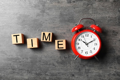 Alarm clock and cubes with word TIME on grey background, flat lay