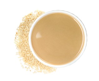 Photo of Tasty sesame paste in bowl and seeds on white background, top view