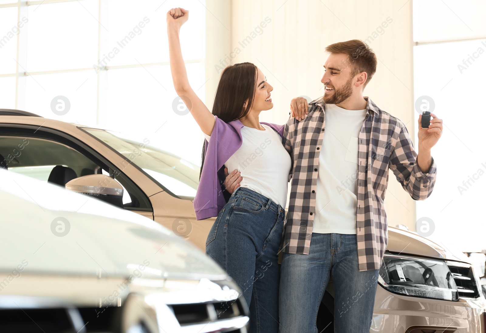 Photo of Happy couple with car key in modern auto dealership