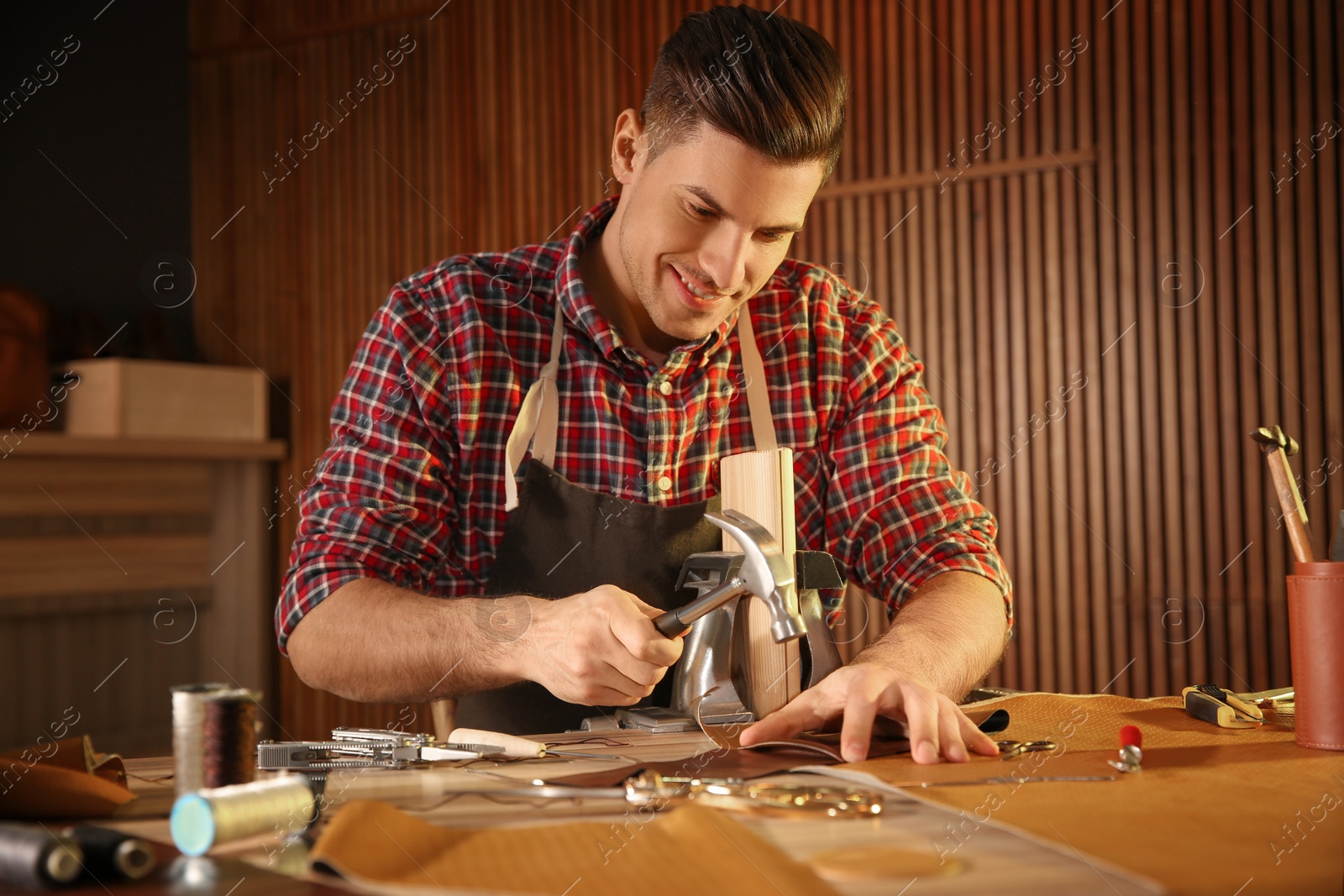 Photo of Man working with piece of leather at table in atelier