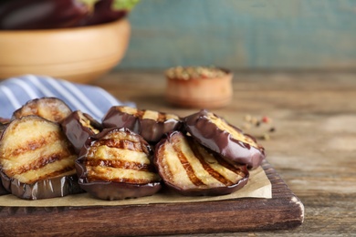 Photo of Delicious grilled eggplant slices on wooden table, closeup