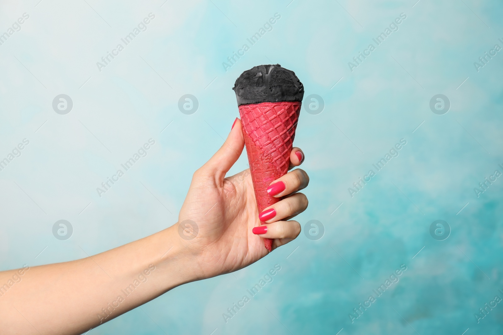 Photo of Woman holding yummy ice cream on color background. Focus on hand