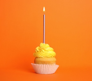 Birthday cupcake with candle on orange background