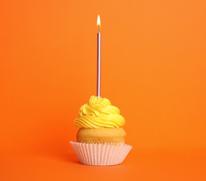 Photo of Birthday cupcake with candle on orange background