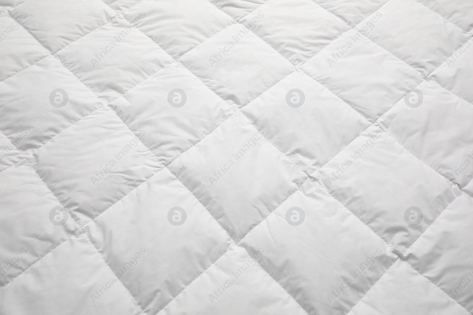 Photo of Soft quilted blanket as background, closeup view