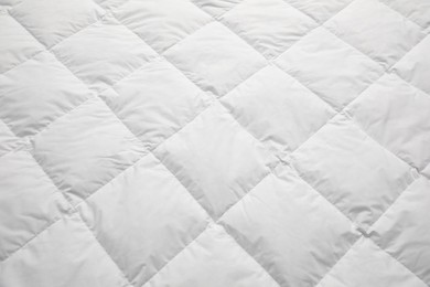 Photo of Soft quilted blanket as background, closeup view