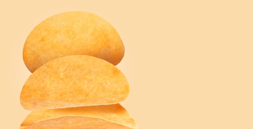 Stack of tasty potato chips on beige background, space for text