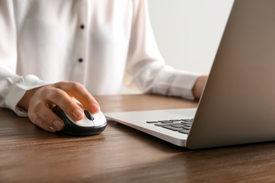 Photo of Woman using computer mouse with laptop at table, closeup