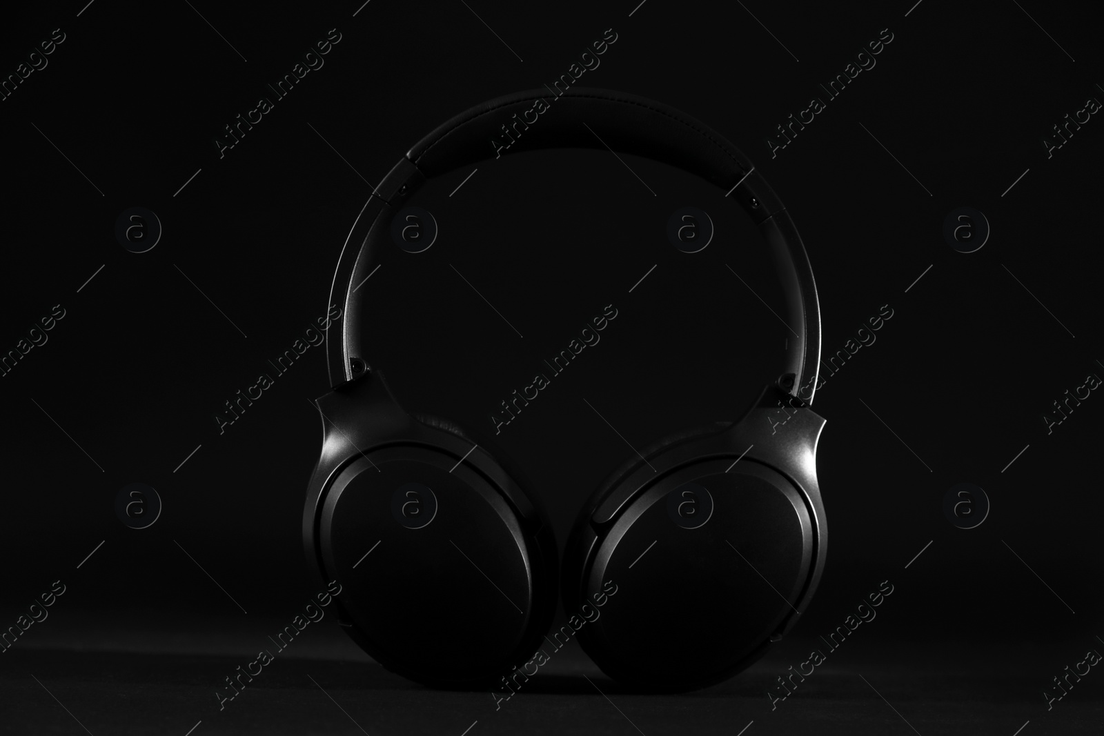 Photo of Stylish modern wireless headphones on black background