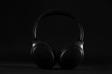 Photo of Stylish modern wireless headphones on black background