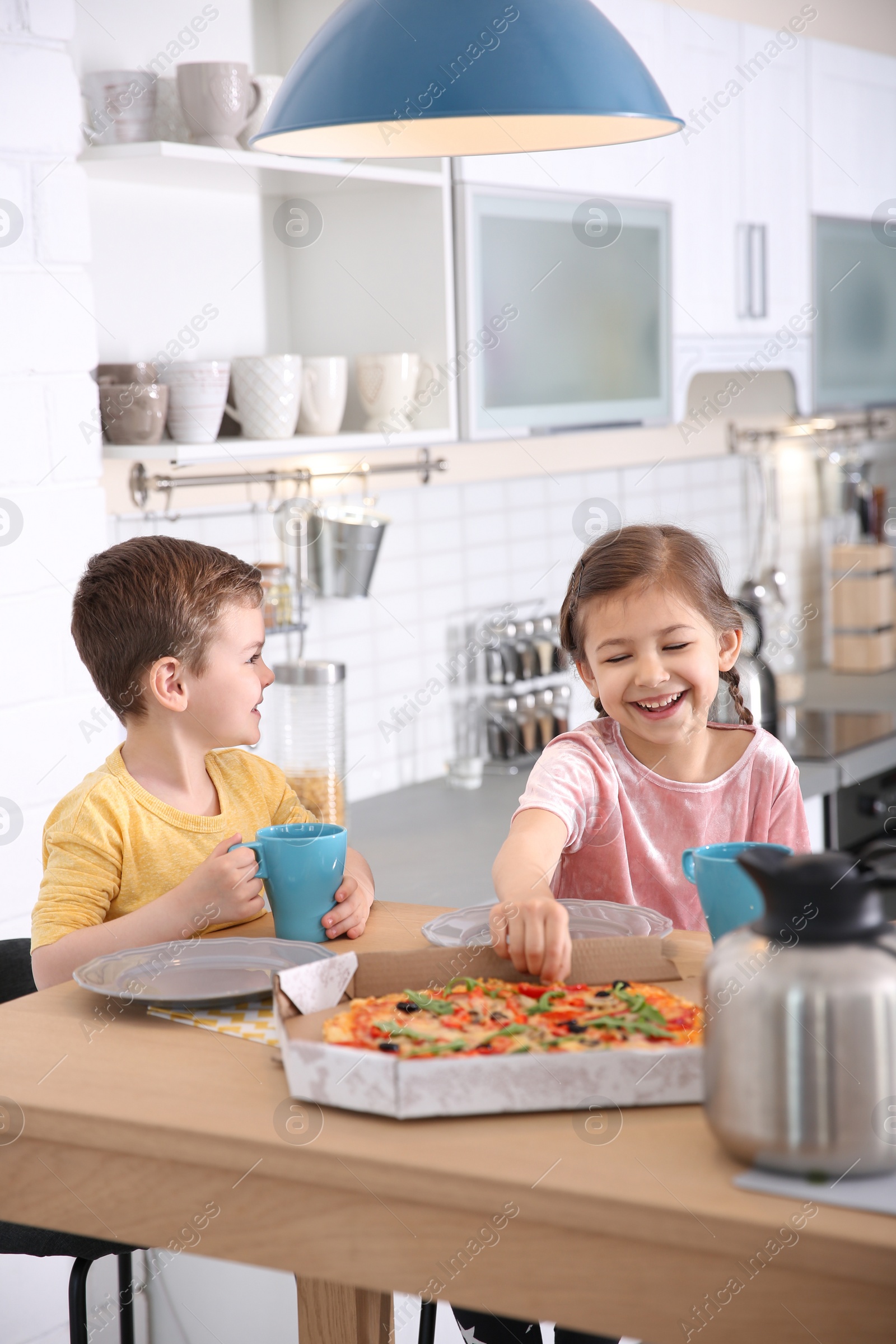 Photo of Cute little kids eating tasty pizza at home