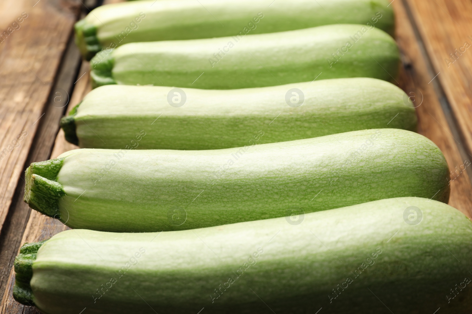 Photo of Raw green zucchinis on wooden table, closeup