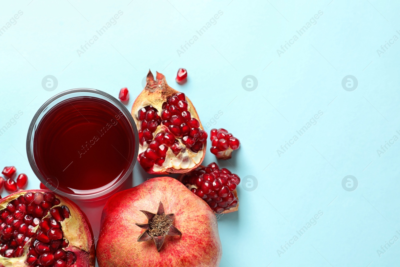 Photo of Glass of pomegranate juice and fresh fruits on color background, top view with space for text