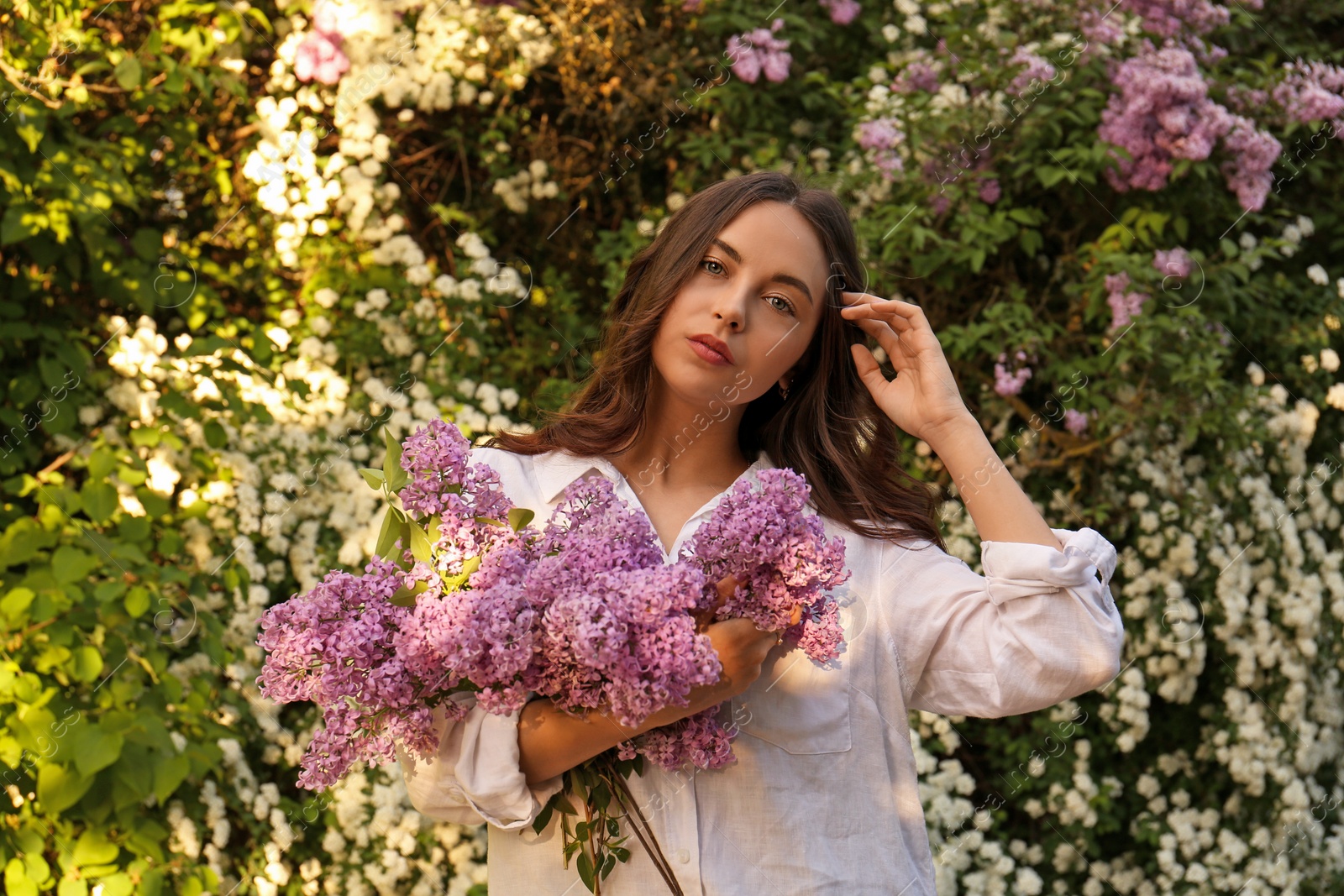 Photo of Attractive young woman with lilac flowers outdoors