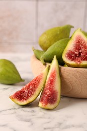 Cut and whole green figs on white marble table