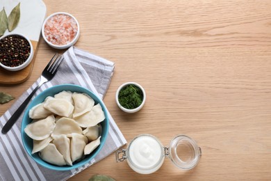 Tasty dumplings in bowl served on wooden table, flat lay. Space for text