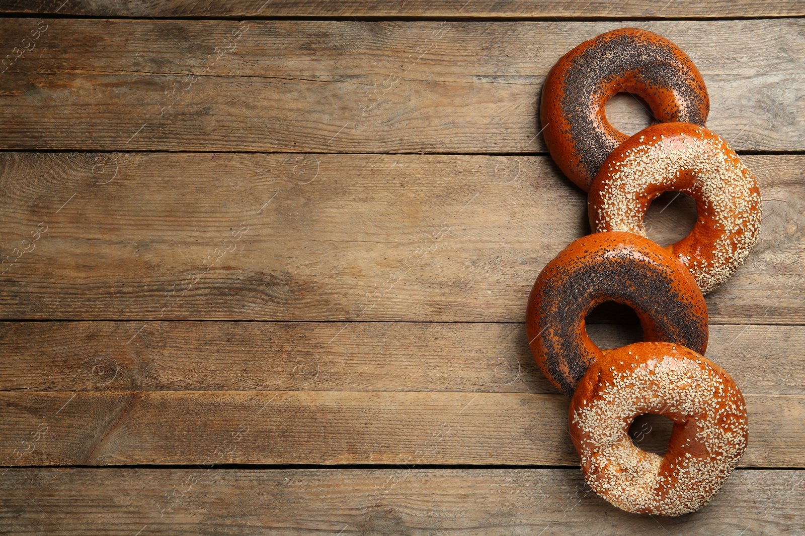 Photo of Many delicious fresh bagels on wooden table, flat lay. Space for text