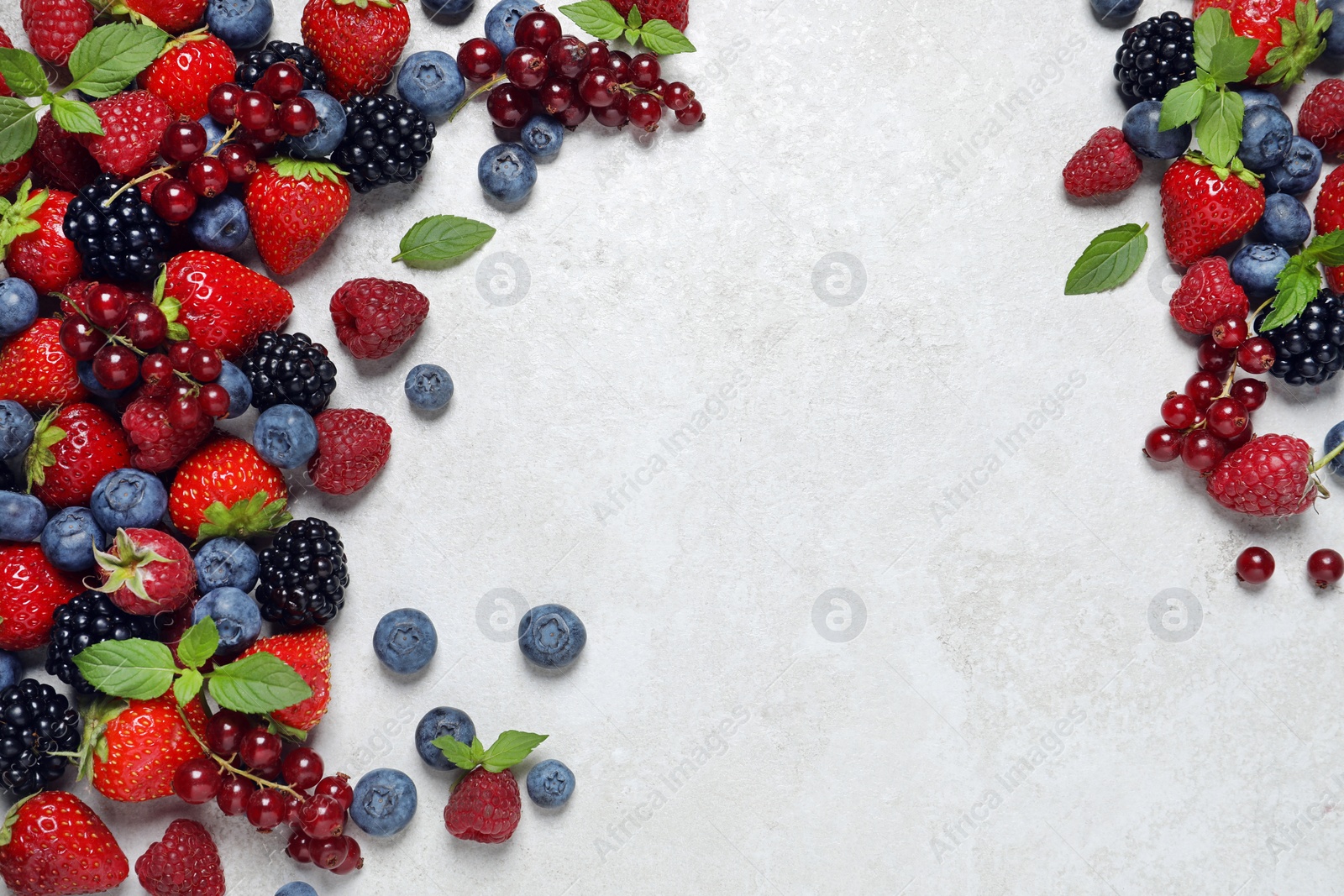 Photo of Many different fresh ripe berries on white textured table, flat lay. Space for text