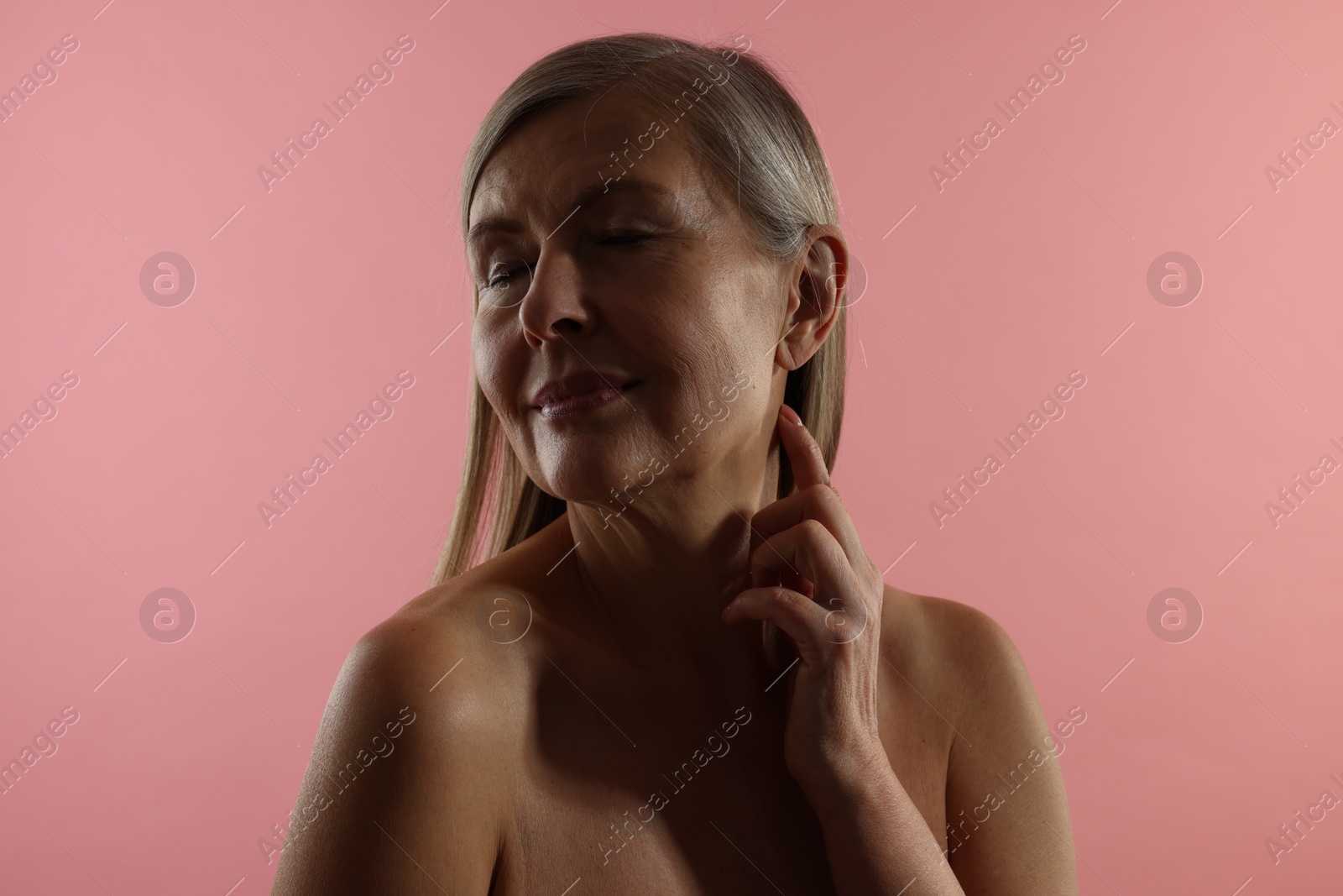 Photo of Beautiful woman touching her neck on pink background