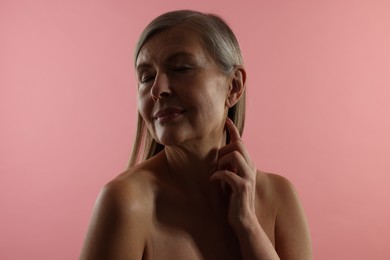 Photo of Beautiful woman touching her neck on pink background