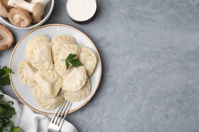 Delicious dumplings (varenyky) with mushrooms and parsley served on light grey table, flat lay. Space for text