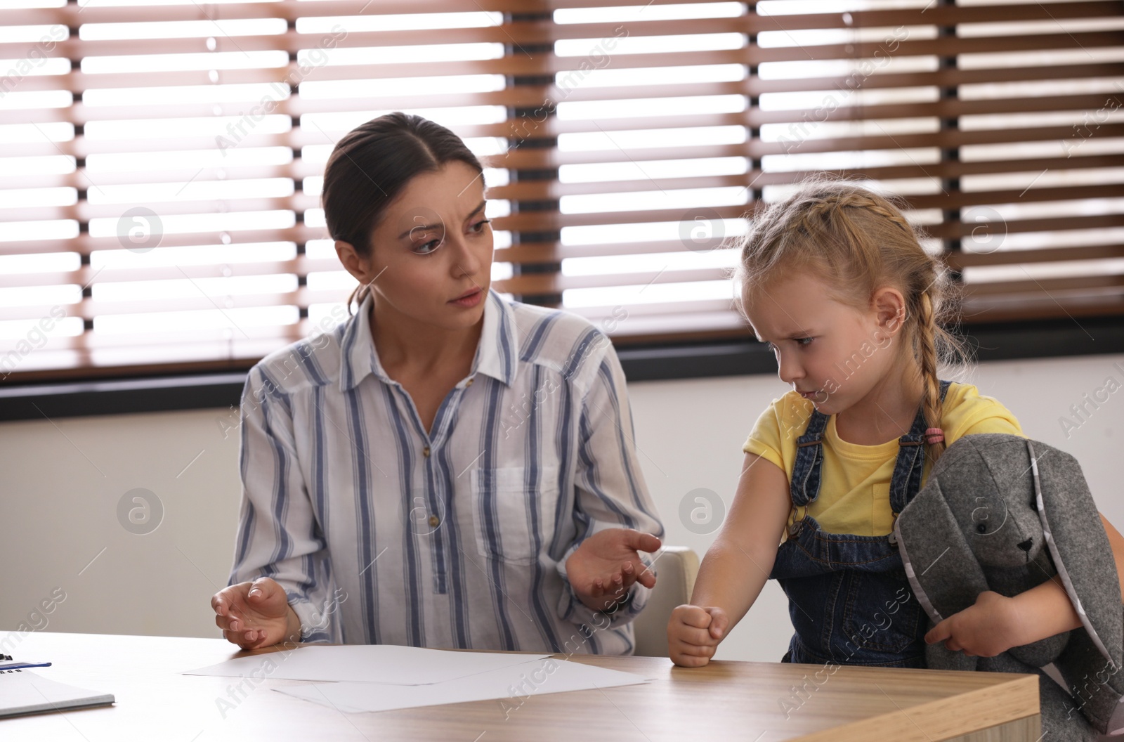 Photo of Little girl and her mother on appointment with child psychotherapist indoors