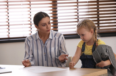 Little girl and her mother on appointment with child psychotherapist indoors