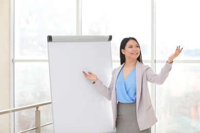 Photo of Business trainer giving presentation on flip chart board indoors