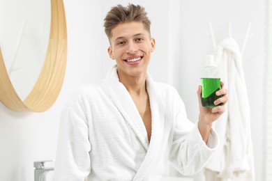 Photo of Young man with mouthwash in bathroom. Oral hygiene