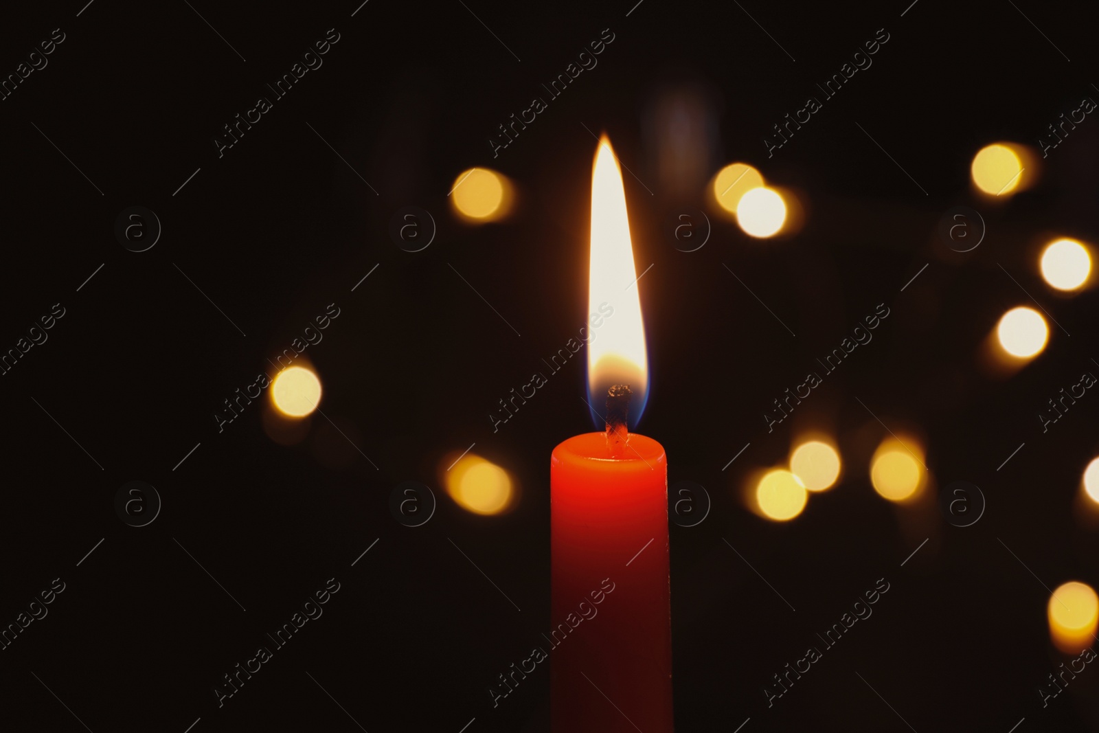 Photo of Wax candle burning on blurred background, closeup