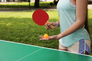 Photo of Young woman playing ping pong in park, closeup. Space for text
